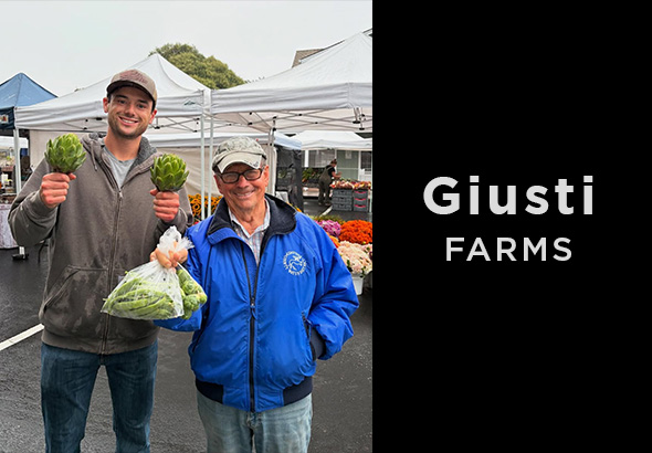 young giusti son holding artichokes with farmer john at farmer’s market